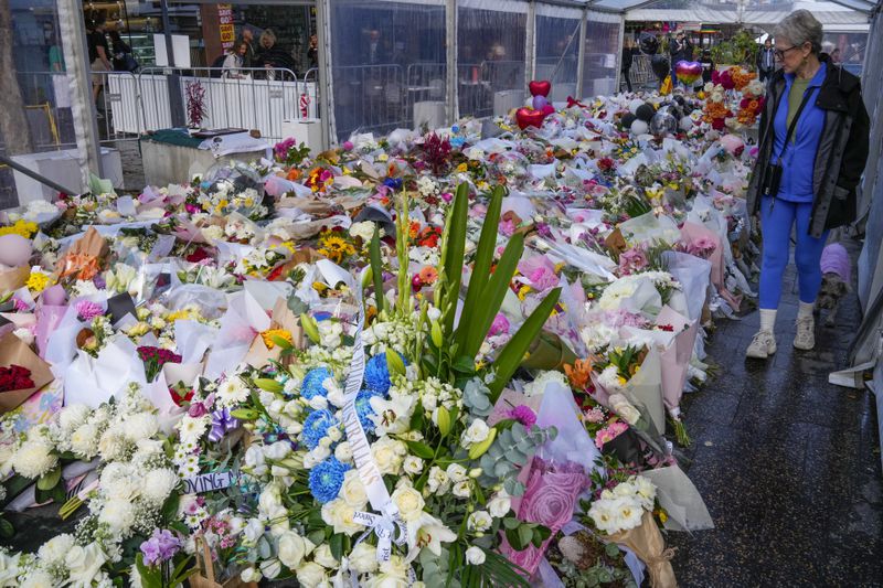 A woman walks past flowers at a tribute for the victims of Saturday's knife attack near a crime scene at Bondi Junction in Sydney, Thursday, April 18, 2024. A Sydney shopping mall has been opened to the public for the first time since it became the scene of a mass stabbing in which six people died, while the Australian prime minister has flagged giving citizenship to an immigrant security guard who was injured while confronting the knife-wielding attacker. (AP Photo/Mark Baker)