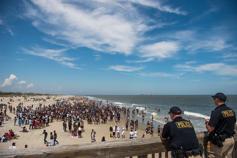Police officers watch a crowd of partiers gather on the beach for Orange Crush Saturday afternoon at Tybee Island. The controversial pop up party was more restricted this year after an alcohol ban was set in place in addition to other laws being enforced. (Photo Courtesy of Josh Galemore/Savannah Morning News)