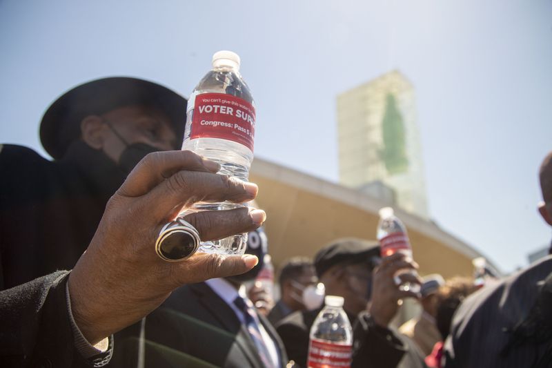 Religious leaders hold bottles of water with labels that read “Voter Suppression” following a press conference earlier this month outside the World of Coca-Cola in downtown Atlanta. (Alyssa Pointer / Alyssa.Pointer@ajc.com)