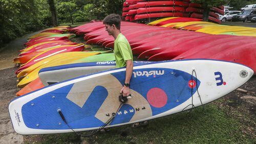 Jase Heins, 18, carries some inflatable paddle boards to the Chattahoochee River bank on May 31, 2017 at Shoot The Hooch, where river goers could rent water vessels. JOHN SPINK/JSPINK@AJC.COM.