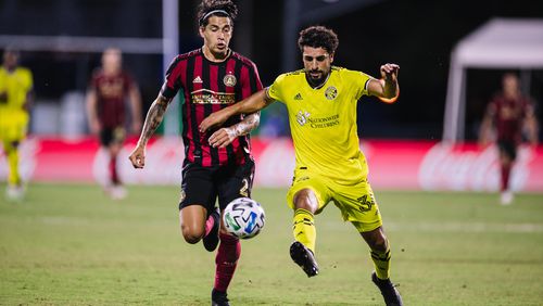 A Columbus attacker drives past Atlanta United defender Franco Escobar Tuesday, July 21, 2020, during MLS tournament game in Orlando, Fla.