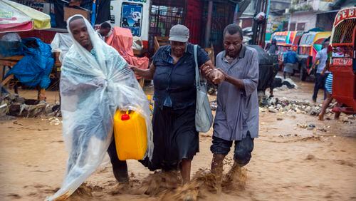 Street vendors wade a flooded street during the passing of Tropical Storm Laura in Port-au-Prince, Haiti, on Sunday. Laura battered the Dominican Republic and Haiti and is heading for a possible hit on the Louisiana coast at or close to hurricane force, along with Tropical Storm Marco.