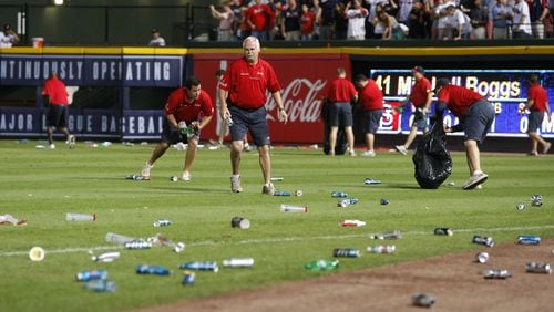 Atlanta Braves ground crew members clean trash off the field after fans littered the area protesting an infield fly rule call on Andrelton Simmons in the eighth inning of the National League wild card game against the St. Louis Cardinals at Turner Field in Atlanta on Friday, Oct. 5, 2012.  CURTIS COMPTON / CCOMPTON@AJC.COM
