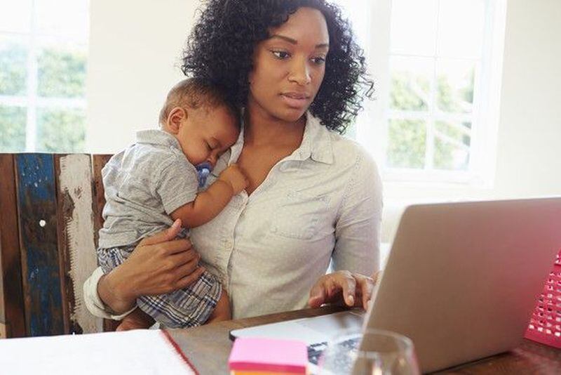 Woman holding a baby at a computer