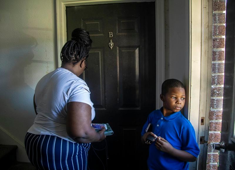 Giovanni Wilcox waits for his mother, Tranisha Wilcox, to open the door to their apartment at Pavilion Place last fall. They and her toddler son CJ lived in a one-bedroom apartment that overlooked another unit where they lived until it burned in a 2020 fire. It remained charred and vacant nearly two years later. (Alyssa Pointer / AJC)
