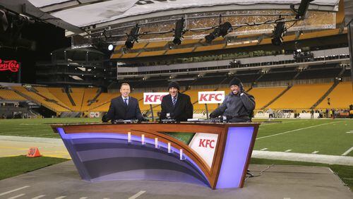 NBC Thursday Night Football announcers Liam McHugh, left, Tony Dungy, center, and Rodney Harrison sit on the sideline set at Heinz Field before an NFL football game between the Pittsburgh Steelers and the Tennessee Titans in Pittsburgh, Thursday, Nov. 16, 2017. (AP Photo/Keith Srakocic)