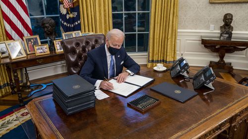 President Joe Biden signs executive orders during his first minutes in the Oval Office of the White House in Washington, on Inauguration Day, Wednesday, Jan. 20, 2021. In 17 executive orders, memorandums and proclamations signed hours after his inauguration, Biden moved swiftly on Wednesday to dismantle Trump administration policies his aides said have caused the “greatest damage” to the nation. (Doug Mills/The New York Times)