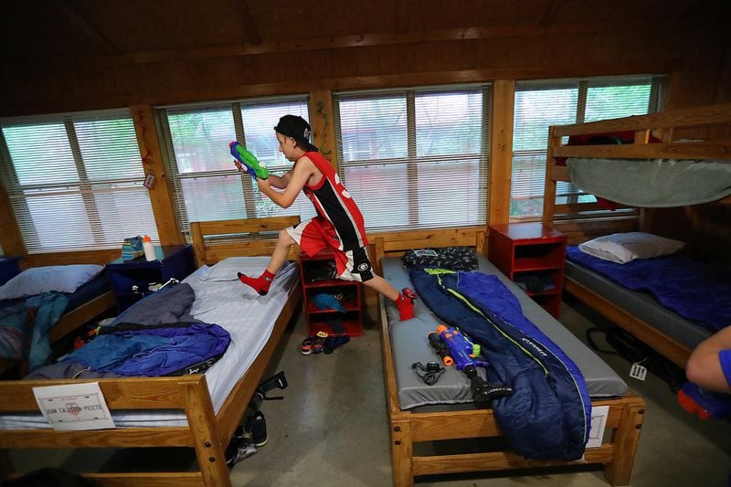 In this summer 2017 file photo, Bronco Reese wastes no time enjoying his independence at on his first day at Camp Twin Lakes running across the bunks in his cabin during a friendly squirt gun battle.

