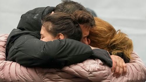 People cry in front of the Vladislav Ribnikar school during a memorial ceremony to mark the first anniversary of a shooting that killed 10 people in Belgrade, Serbia, Friday, May 3, 2024. (AP Photo/Darko Vojinovic)