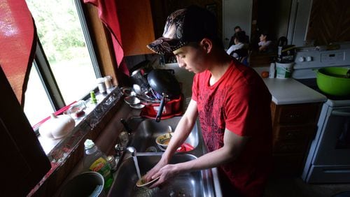 Ilsiar Jimenez, 18, washes dishes after dinner Wednesday at his guardian’s home in Flowery Branch. Last year, he traveled by foot and vehicle for two months from his native Guatemala to the U.S. border, becoming one of a growing number of children who are illegally entering the U.S. without their parents. President Barack Obama earlier this week called the rising number an “urgent humanitarian situation.” HYOSUB SHIN / HSHIN@AJC.COM