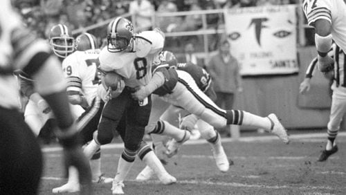 Quarterback Archie Manning (8) of the New Orleans Saints struggles in the clutches of defensive end Claude Humphrey (87) of the Atlanta Falcons in first half action at Atlanta-Fulton County Stadium in Atlanta, Ga., Dec. 18, 1977. Humphrey's tackle dropped Manning near the Saints goal line. (AP Photo/Charles Kelly)