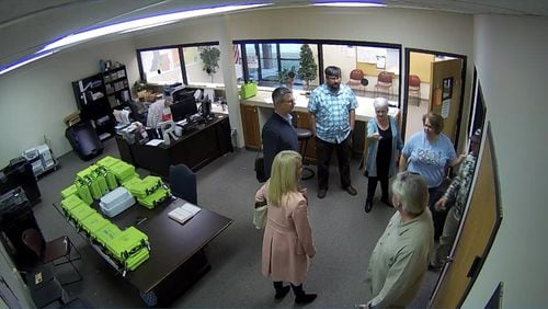 Surveillance video of the Coffee County election office shows green voter check-in tablets, called PollPads, on a table while tech experts and supporters of then-President Donald Trump examine election equipment on Jan. 7, 2021, the day after a mob attacked the U.S. Capitol. 
From left: computer analysts Paul Maggio, Jennifer Jackson and Jim Nelson of the data firm SullivanStrickler; Cathy Latham, a member of the Georgia Republican Party's executive committee; Ed Voyles, a former Coffee County elections board member; Misty Hampton, the county's elections director; and Eric Chaney, a Coffee County elections board member. Source: Coffee County