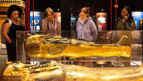 Visitors view replica gold coffins at the “Tutankhamun: His Tomb and His Treasures” exhibit at Exhibition Arts Center Atlanta in Doraville on Wednesday, October 4, 2023. (Arvin Temkar / arvin.temkar@ajc.com)