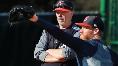 Braves new pitching coach Rick Kranitz is prominent in the background as starter Mike Foltynewicz throws in the bullpen in spring camp. (Staff photo by Curtis Compton/ccompton@ajc.com)