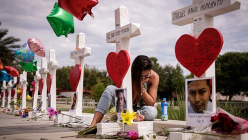 A woman writes a note on a cross at a memorial outside the Orlando Regional Medical Center on June 17, 2016. The memorial included a cross for each of the 49 victims killed in the  Pulse nightclub shooting. Not including the Pulse victims, a new report finds 2016 was the deadliest year ever for the LGBTQ community.