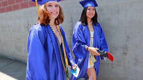 Rachel Rigsbee (left) and Emily Guo (right) walk to their graduation ceremony for Chattahoochee High School on May 21, 2019, at Ameris Bank Amphitheatre in Alpharetta. Guo is heading to Stanford to study the intersection of science, technology and society. Rigsbee will study environmental engineering at Georgia Tech. CURTIS COMPTON / CCOMPTON@AJC.COM