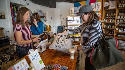 Owner Jen Singh (L) rings up Susan Kent in her shop, the Garage Door Studio, during Small Business Saturday in Avondale Estates on Nov. 30, 2019. STEVE SCHAEFER / SPECIAL TO THE AJC