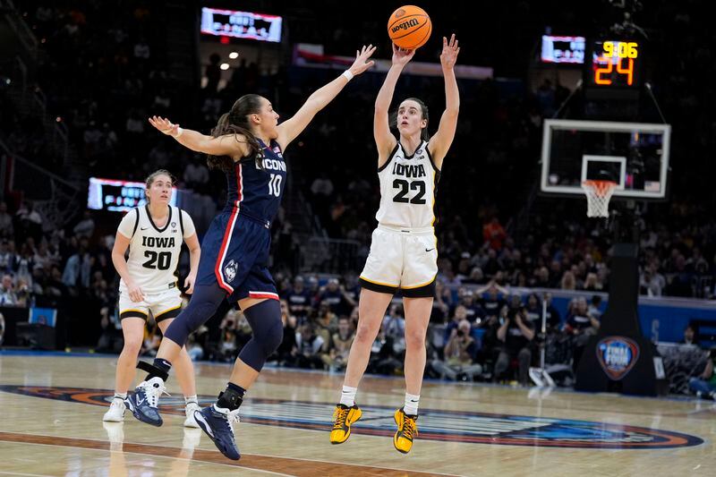 Iowa guard Caitlin Clark (22) shoots a three-point basket over UConn guard Nika Muhl (10) during the second half of a Final Four college basketball game in the women's NCAA Tournament, Friday, April 5, 2024, in Cleveland. (AP Photo/Morry Gash)