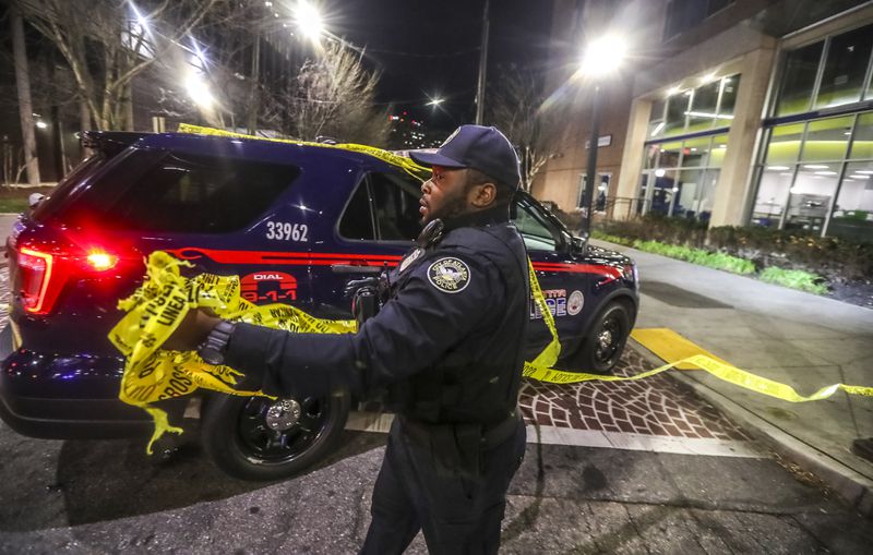 An officer gathers crime scene tape after one person died and another was injured Dec. 15 near Georgia State University’s campus.

