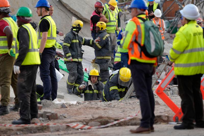 Emergency workers on the scene of a building collapse in the city of George, about 400 kilometers (250 miles) east of Cape Town, South Africa, Tuesday, May 7, 2024. Rescue teams trying to find dozens of construction workers missing since a multi-story apartment complex collapsed in a coastal city in South Africa have made contact with 11 people buried alive beneath the mangled wreckage, authorities said Tuesday. (AP Photo/Nardus Engelbrecht)