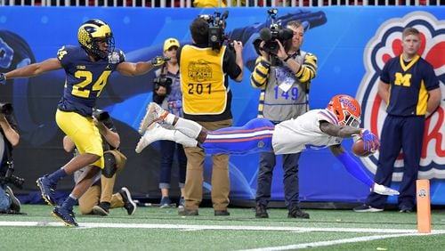 Florida running back Kadarius Toney (4) dives to the end zone after he was pushed by Michigan defensive back Lavert Hill (24) in the Chick-fil-A Peach Bowl at Mercedes-Benz Stadium on Saturday, Dec. 29, 2018. HYOSUB SHIN / HSHIN@AJC.COM