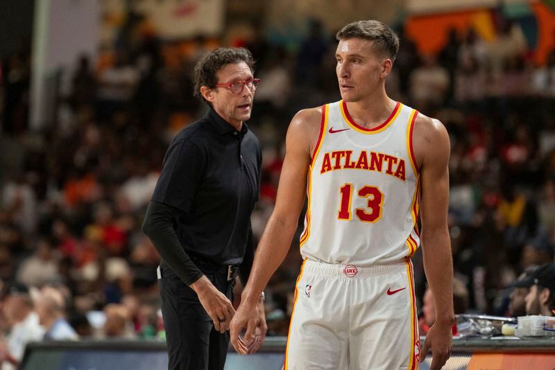 Atlanta Hawks head coach Quin Snyder, left, speaks to guard Bogdan Bogdanovic (13) during the first half of a preseason NBA basketball game against the New Orleans Pelicans, Saturday, Oct. 14, 2023, in College Park, Ga. (AP Photo/Hakim Wright Sr.)
