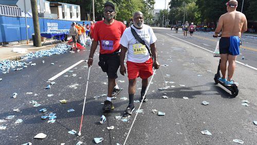 Willard Walker (left) and his brother John W. Smith, both legally blind, were among the last group of walkers and runners to make their way down Peachtree Road during the 50th AJC Peachtree Road Race on the Fourth of July. (Photo: Hyosub Shin / Hyosub.Shin@ajc.com)