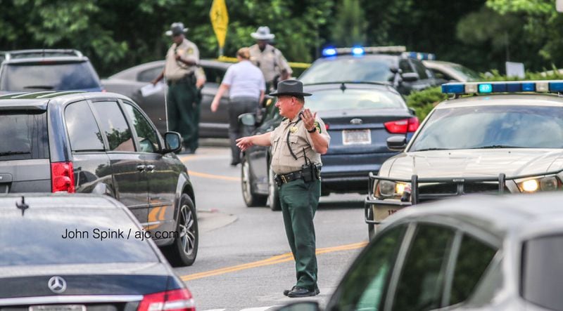 A Douglas County sheriff's deputy directs traffic away from an active crime scene Wednesday morning where a shooting victim was found lying in the middle of a roadway. JOHN SPINK / JSPINK@AJC.COM