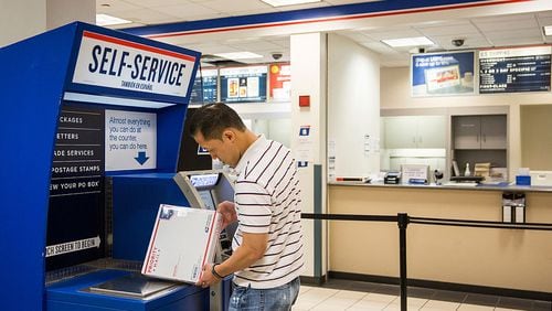 NEW YORK, NY - SEPTEMBER 25: A man uses a self service machine at a United States Post Office (USPS) on September 25, 2013 in New York City. The USPS announced today that they're considering raising the price of stamps by 3 cents. (Photo by Andrew Burton/Getty Images)