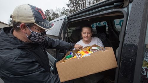 A volunteer hands out food at a food distribution event in Peachtree City in December. Demand at food banks has risen since the pandemic hit. (Jenni Girtman/Atlanta Journal-Constitution/TNS)