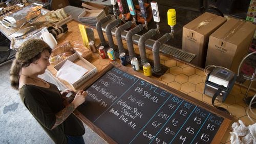 Angela Riley, brand manager at Wild Beer Heaven Brewery, works on a new beer menu in preparation for Friday, when the brewery will be allowed to sell beer directly to customers. STEVE SCHAEFER / SPECIAL TO THE AJC