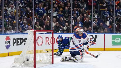 Vancouver Canucks' Conor Garland, back, scores the winning goal against Edmonton Oilers goalie Stuart Skinner (74) as Darnell Nurse (25) defends during the third period of Game 1 of a second-round NHL hockey Stanley Cup playoffs series, Wednesday, May 8, 2024, in Vancouver, British Columbia. (Darryl Dyck/The Canadian Press via AP)