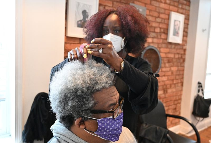 Nekesa Smith, a local stylist and hair expert, measures the length of AJC reporter Ernie Suggs’ hair as she gives him advice about his hair and growing an Afro at her shop in College Park on Friday, Feb. 12, 2021. (Hyosub Shin / Hyosub.Shin@ajc.com)