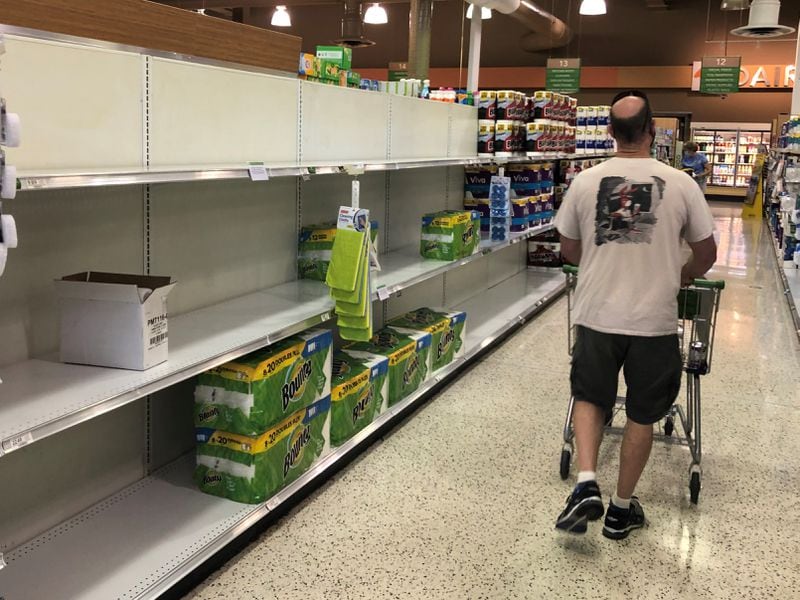 A shopper wanders by stripped paper towel shelves in a Vinings grocery store in early September. By the end of the month, most retailers' shelves were again showing plenty of the product.