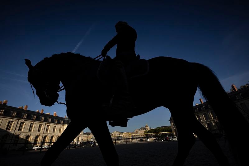A horsewoman trains with her horse in the main courtyard of the royal stables, in Versailles, Thursday, April 25, 2024. More than 340 years after the royal stables were built under the reign of France's Sun King, riders and horses continue to train and perform in front of the Versailles Palace. The site will soon keep on with the tradition by hosting the equestrian sports during the Paris Olympics. Commissioned by King Louis XIV, the stables have been built from 1679 to 1682 opposite to the palace's main entrance. (AP Photo/Aurelien Morissard)