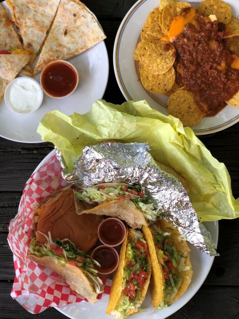 Taco Pete Bistro offers delicious Mexican-American food at good value. Seen here are a cheese quesadilla, chili-cheese nachos, tacos, a taco burger, and (hidden under the yellow paper) a chicken burrito. Wendell Brock for The Atlanta Journal-Constitution