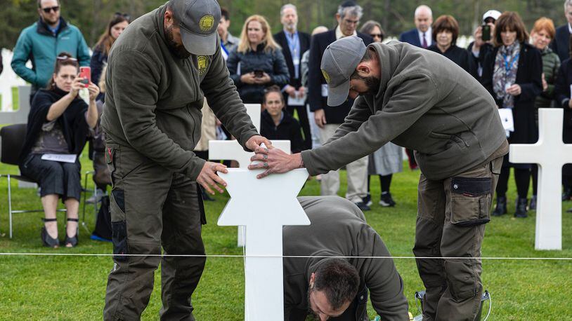 Workers replace a cross with a Star of David at a military cemetery. (Photo courtesy of Operation Benjamin)