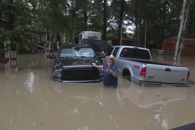 A man waves at Texas Parks & Wildlife Department game wardens as they arrive by boat to rescue residents from floodwaters in Liberty County, Texas. (AP Photo/Lekan Oyekanmi)