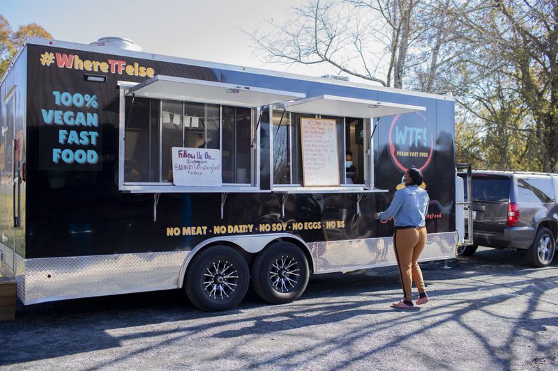 Aisha Campbell orders lunch from the WTF Vegan food truck outside of Rooted Trading Co. in Powder Springs, Georgia, on Thursday, December 10, 2020. Campbell went plant-based a year ago and was so excited to finally see a vegan food truck in Powder Springs. The city is embarking on a plan that would allow more businesses and mixed-used residences to possibly open in its downtown. The city's plan hopes to promote growth and redevelopment while maintaining its small-town charm and atmosphere. (Rebecca Wright for the Atlanta Journal-Constitution)  