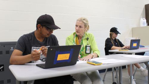 Instructor Andra Cruse (center) works with students Sergio Vergas (left) and Ella Kitchen on math concepts.