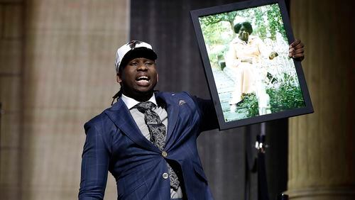 UCLA's Takkarist McKinley carries a photograph of his grandmother onstage after being selected by the Atlanta Falcons during the first round of the 2017 NFL football draft, Thursday, April 27, 2017, in Philadelphia.