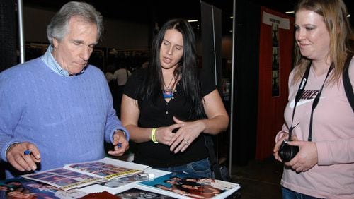Television legend Henry Winkler (L) autographs an event booklet for Ange Alex (C) and April Bumps (R) at the Wizard World Atlanta Comic Con at Cobb Galleria Centre on Saturday, Dec. 5, 2010.