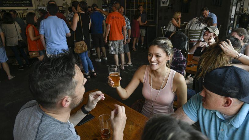 Emily Handziuk of Atlanta (second from right) holds a beer while talking to friends Ashton Pierre (left) and Jonathan Peardon (right), also from Atlanta, at Gate City Brewing recently. CONTRIBUTED BY JOHN AMIS