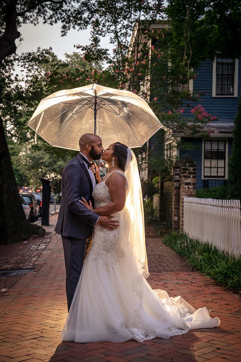 Newlyweds Colin and Erica Hardin kiss under an umbrella as they pose for photos following their Savannah wedding on July 10, 2021, at the Charles Morris Center.