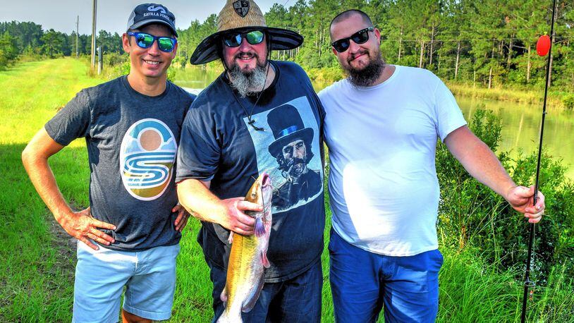 Zack Gowan (from left, owner of Georgia Sea Grill, Satilla Ponds and Potlikker Farms), Tim Lensch (executive chef at Georgia Sea Grill) and Eric Miller (Satilla Ponds farm operator) pose with a just-caught catfish Sunday morning. Chris Hunt for The Atlanta Journal-Constitution