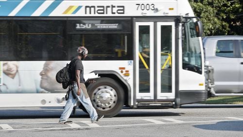A pedestrian crosses in front of a MARTA bus in Dunwoody. (Bob Andres / robert.andres@ajc.com)