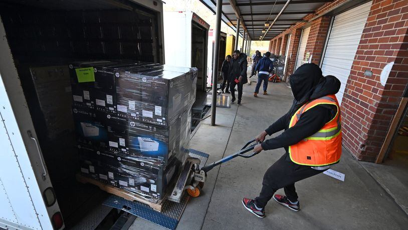 An elections worker unloads a batch of new voting machines at Fulton County Election Preparation Center in Atlanta on Tuesday, Jan. 21, 2020. Truckloads of voting machines are arriving at a large Atlanta-area warehouse, where workers are unloading piles of cardboard boxes before a critical deadline: the March 24 presidential primary. (Hyosub Shin / Hyosub.Shin@ajc.com)