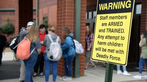 03/25/19 - Dublin -  Students wait for their parents to pick them up at East Laurens Middle-High School on Monday behind a sign that warns visitors of the school that staff members are armed with weapons to protect students. Jenna Eason for The Atlanta Journal-Constitution