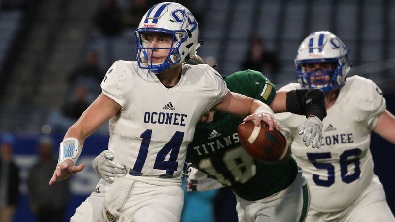 Oconee County quarterback Max Johnson (14) attempts a pass against the pressure from Blessed Trinity linebacker Michael Mitchler (18) in the first half of the Class AAAA high school football state title at Georgia State Stadium Saturday, December 14, 2019 in Atlanta. (JASON GETZ/SPECIAL TO THE AJC)