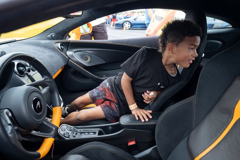 Aziah Simmons, 9, checks out the inside of a McLaren 570S before going for a ride around the Atlanta Motorsports Park racetrack on Saturday. Aziah was born with a restricted airway and has undergone numerous surgeries for it, his mother said. (Ben Gray for the Atlanta Journal-Constitution)